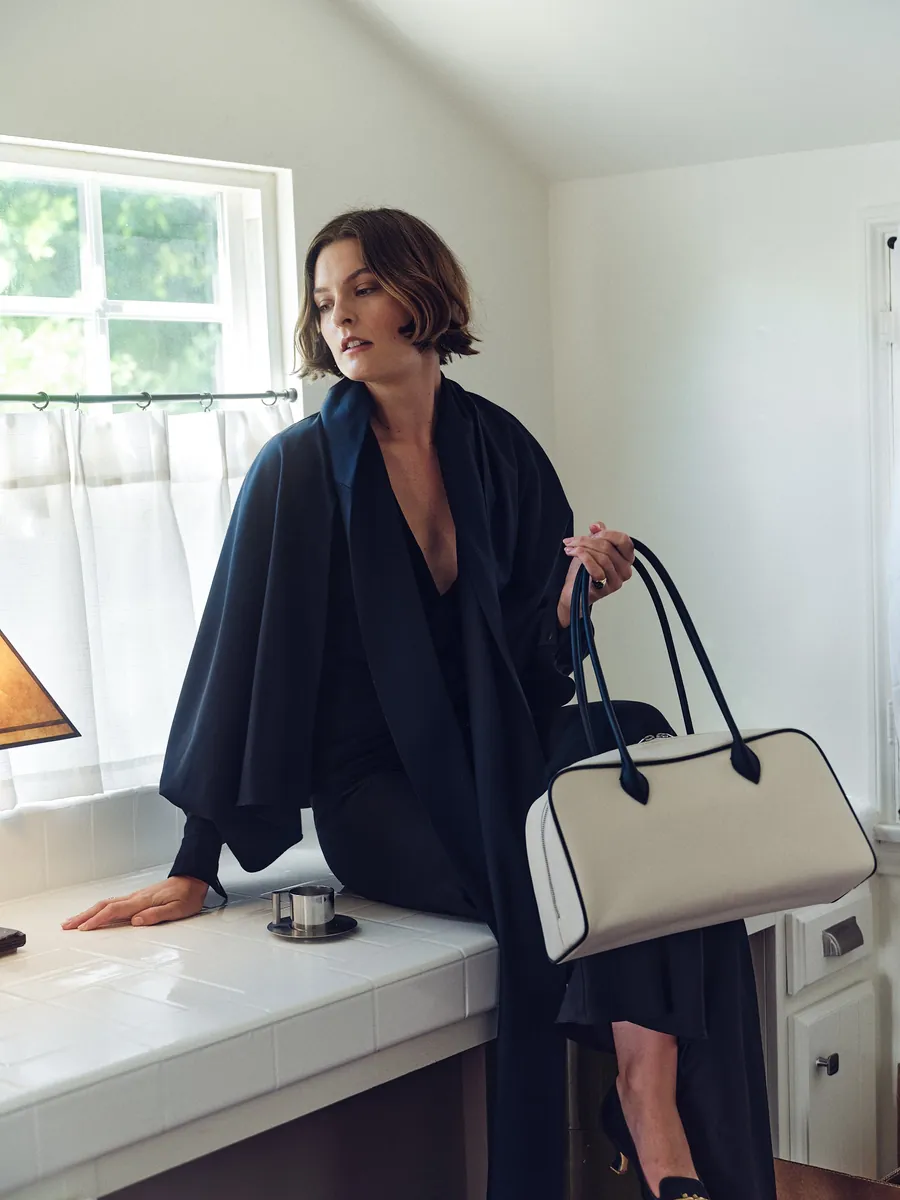 Model with a leather shoulder bag in a sunlit kitchen